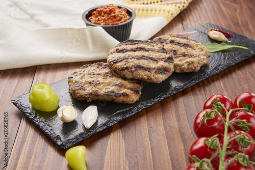 Grilled Veal minced meat with spices on black stone and wooden background 