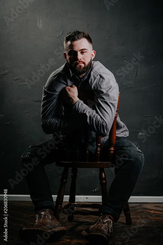 Brutal handsome man sitting on chair