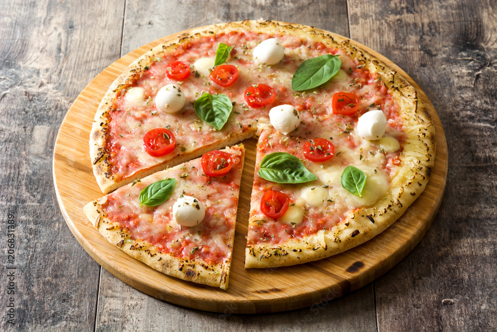 Italian pizza slice with tomatoes, cheese and basil on wooden table
