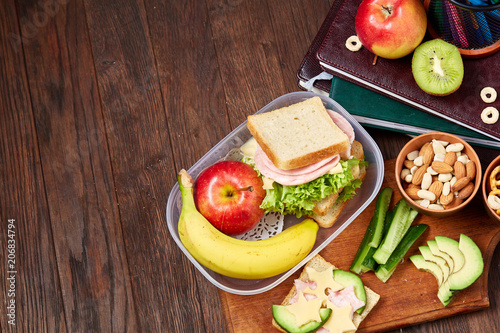 фотографія Concept of school lunch break with healthy lunch box and school supplies on wooden desk, selective focus