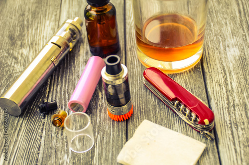 Still life with e-cig and jiuce on the wooden background photo