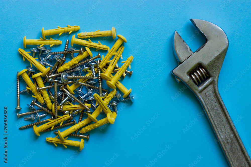 A bunch of different nails and a wrench on a blue background A bunch of different nails and a wrench on a blue background