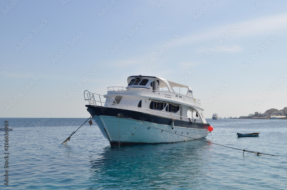 Yacht and azure coast with white sand, clean and clear blue water on a sunny day
