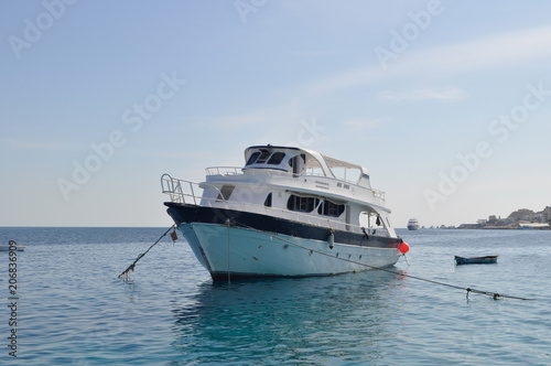 Yacht and azure coast with white sand, clean and clear blue water on a sunny day © alinaait