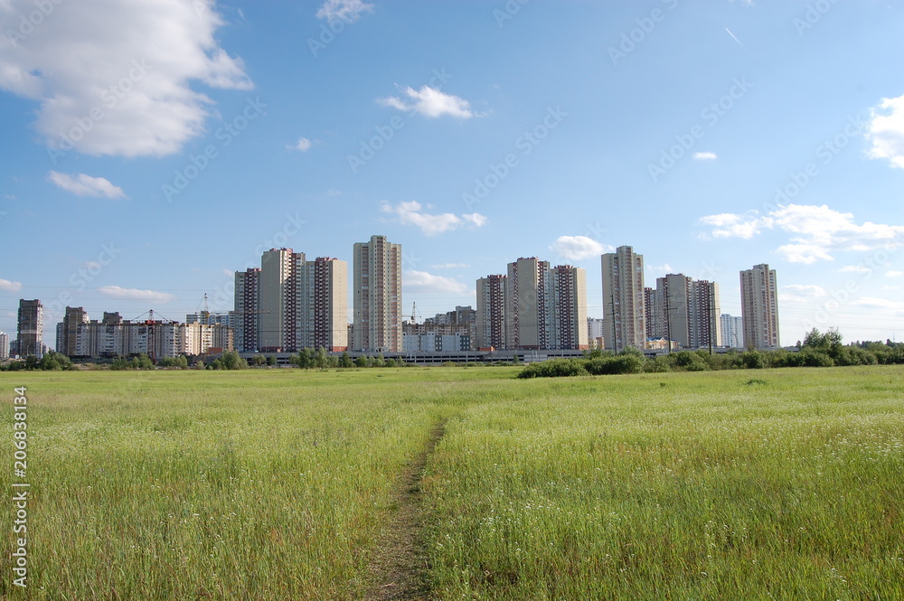 high residential buildings on the background of a large field and a blue sky high residential buildings on the background of a large field and a blue sky