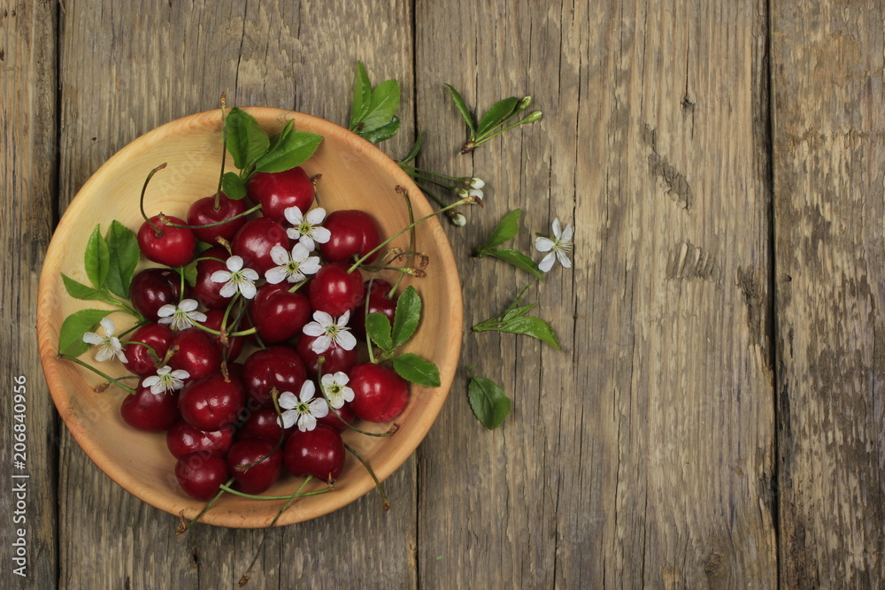red cherries in wooden plate on wooden background