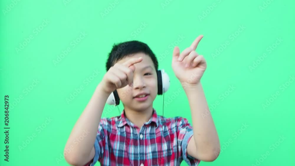 Young asian boy wearing hesdset and dancing in front of green screen Young asian boy wearing hesdset and dancing in front of green screen