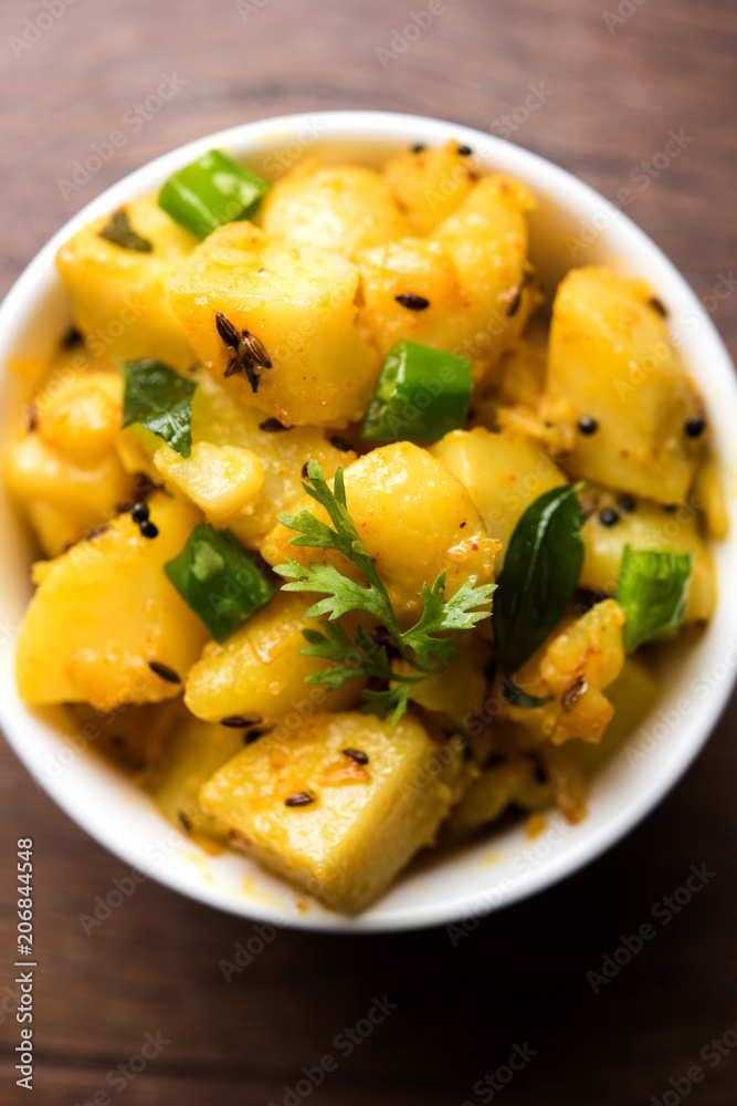 Chatpate Masala Aloo Sabzi fry OR Bombay potatoes served in a bowl, selective focus