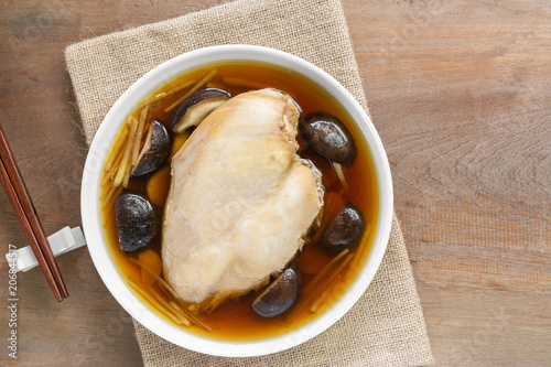steamed chicken breast with soy sauce in a ceramic dish on wooden table, top view. homemade style healthy food concept.