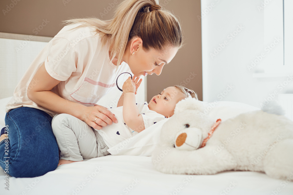Mother with baby lying on the bed in a white room. Mother with baby lying on the bed in a white room.