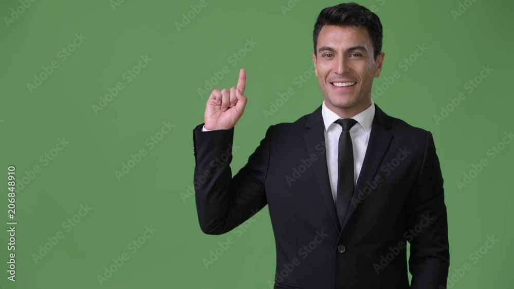 Young handsome Hispanic businessman against green background Young handsome Hispanic businessman against green background