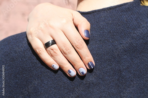 Beautiful female hand with extraordinary manicure. Creative nail design in blue. Ultra stylish colors of nail polish.