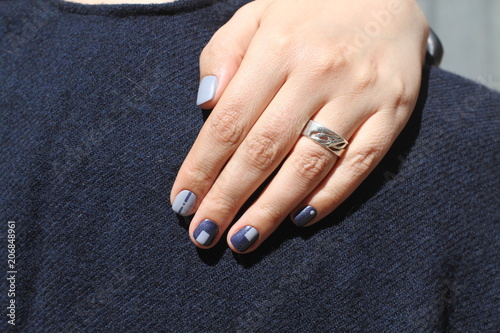 Beautiful female hand with extraordinary manicure. Creative nail design in blue. Ultra stylish colors of nail polish.
