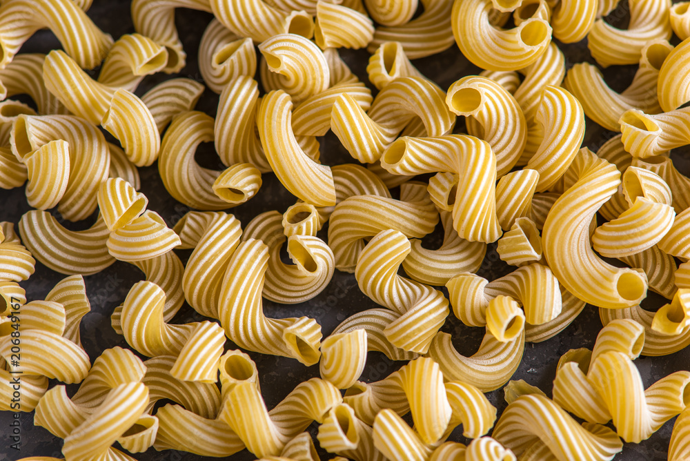 Uncooked italian pasta in the form of spirals on a dark background. Concept of composition of food design. Uncooked italian pasta in the form of spirals on a dark background. Concept of composition of food design.