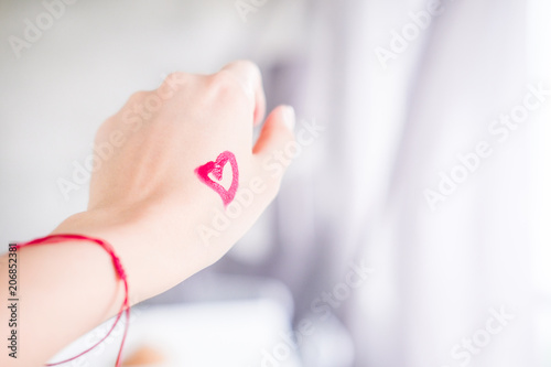 Heart drawn with lipstick on woman's hand