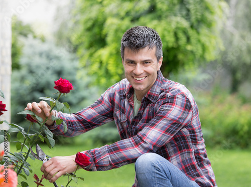 Gardener with scissors and red rose