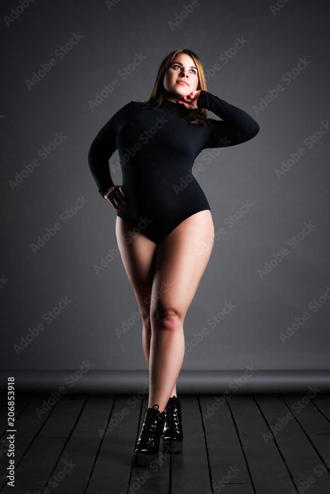 Foto de Plus size sexy model in black bodysuit, fat woman on gray studio  background, overweight female body do Stock