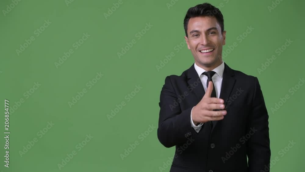 Young handsome Hispanic businessman against green background Young handsome Hispanic businessman against green background