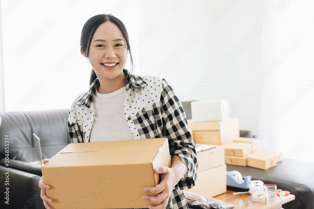 Beautiful girl holding cardboard box for shipping orders - start up small business owner writing address on cardboard box at workplace.small business entrepreneur SME or freelance asian woman working Beautiful girl holding cardboard box for shipping orders - start up small business owner writing address on cardboard box at workplace.small business entrepreneur SME or freelance asian woman working