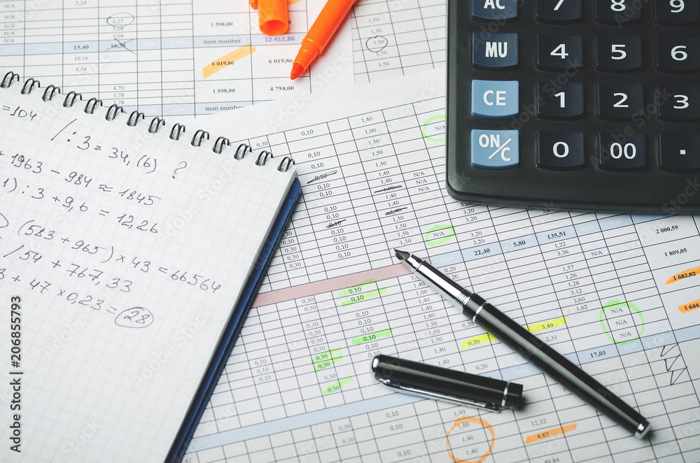 Accounting records in tables, a paper notebook with profit calculations, a pen and a calculator Accounting records in tables, a paper notebook with profit calculations, a pen and a calculator
