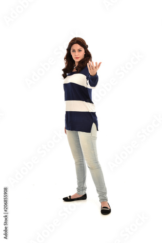  full length portrait of girl wearing striped blue and white jumper and jeans. standing pose on white studio background