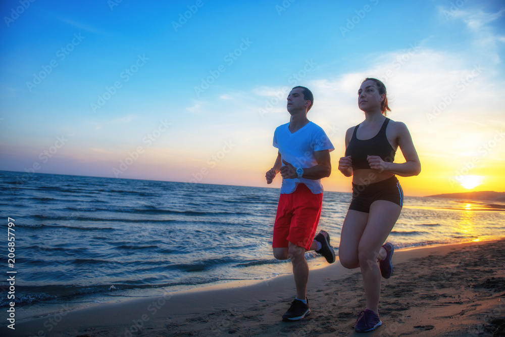 Man and women running on tropical beach at sunset Man and women running on tropical beach at sunset