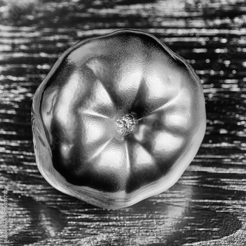 Metallic silver tomato concept on silver wood background. minimal idea food and vegetable concept. An idea creative to produce work within an advertising marketing communications or artwork design.