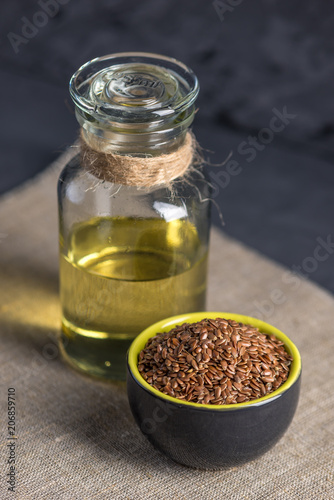 Flax seeds in a pile and linseed golden oil in a glass bottle on the table. Healthy diet with omega 3 fatty acids.