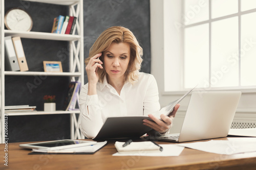 Thoughtful businesswoman reading document at office desktop