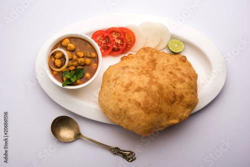 Chole Bhature or Chick pea curry and Fried  Puri served in terracotta crockery over white background. selective focus photo