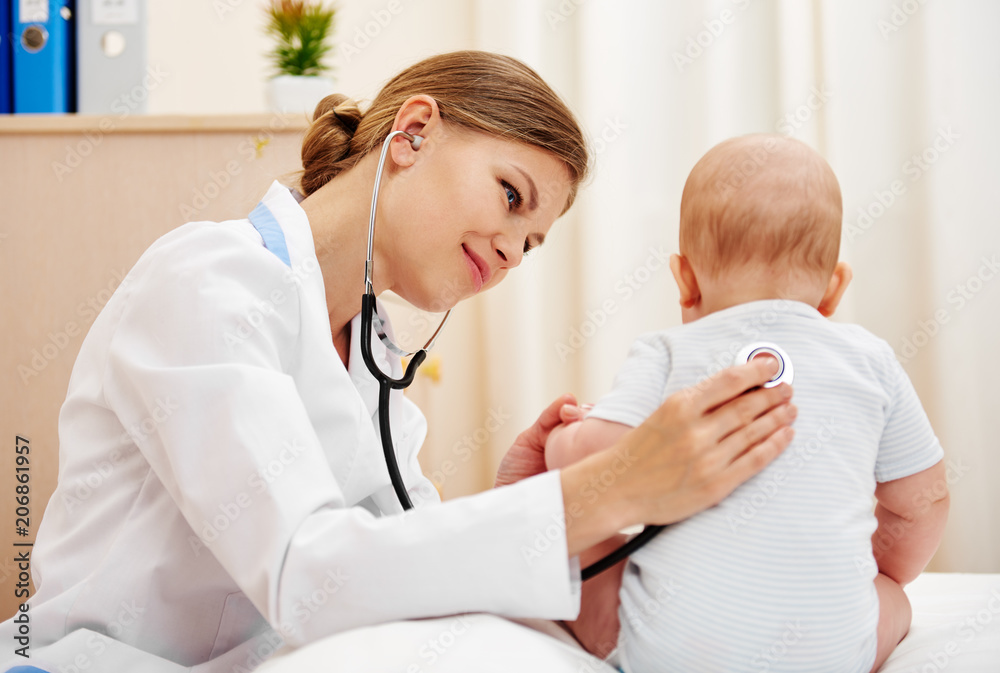 Fototapeta premium Young doctor examining baby infant with stethoscope. 