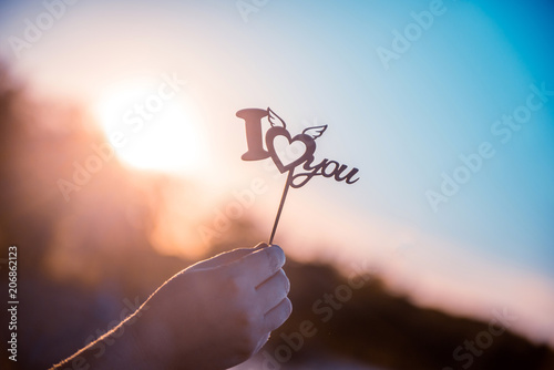 Quadro su tela Girl holding the inscription I love you, on the sunset background