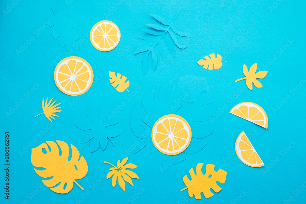 Lemon slices and tropical leaves pattern on a bright blue background. Papercraft flat lay header. Lemon slices and tropical leaves pattern on a bright blue background. Papercraft flat lay header.