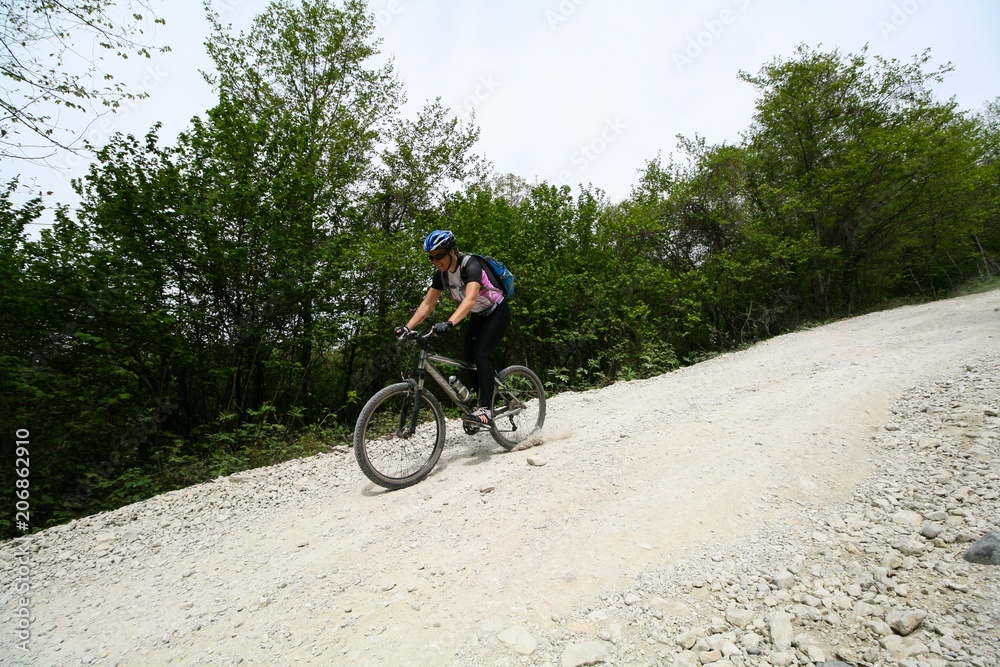 Young woman down on a bike on a dirt road, Sochi