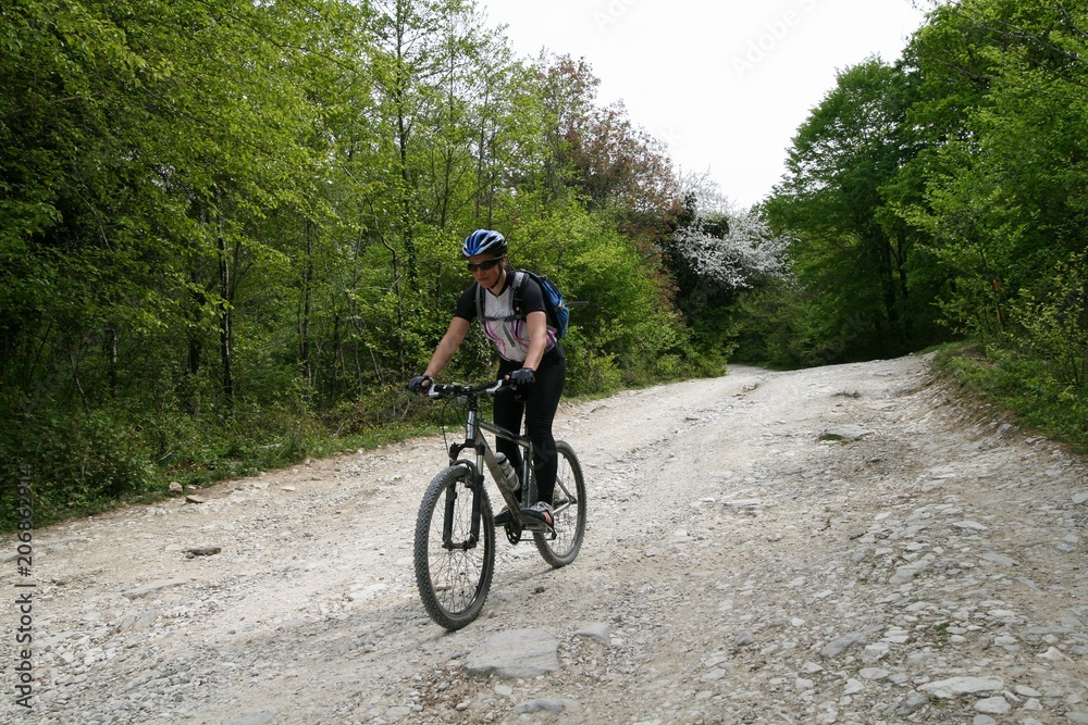 Young woman down on a bike on a dirt road, Sochi