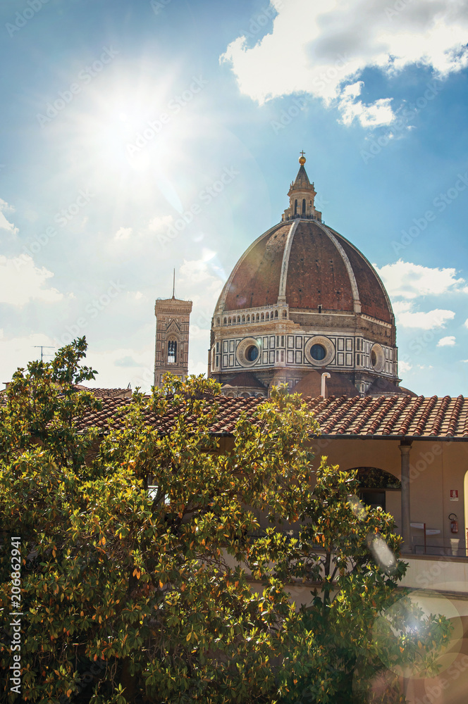 Close-up of roof in building, tree and Cathedral dome with sunny blue sky in the city of Florence, the famous and amazing capital of the Italian Renaissance. In the Tuscany region. Retouched photo