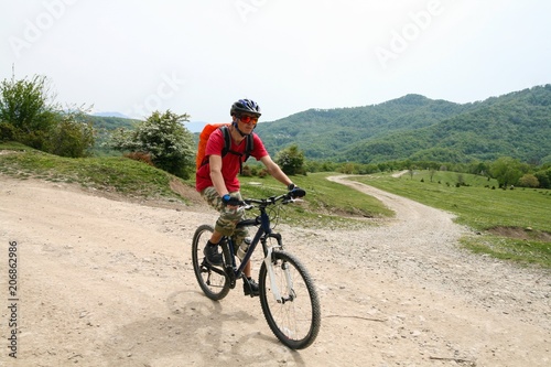 Fototapeta Naklejka Na Ścianę i Meble -  Cyclist rides on a dirt road in the mountains
