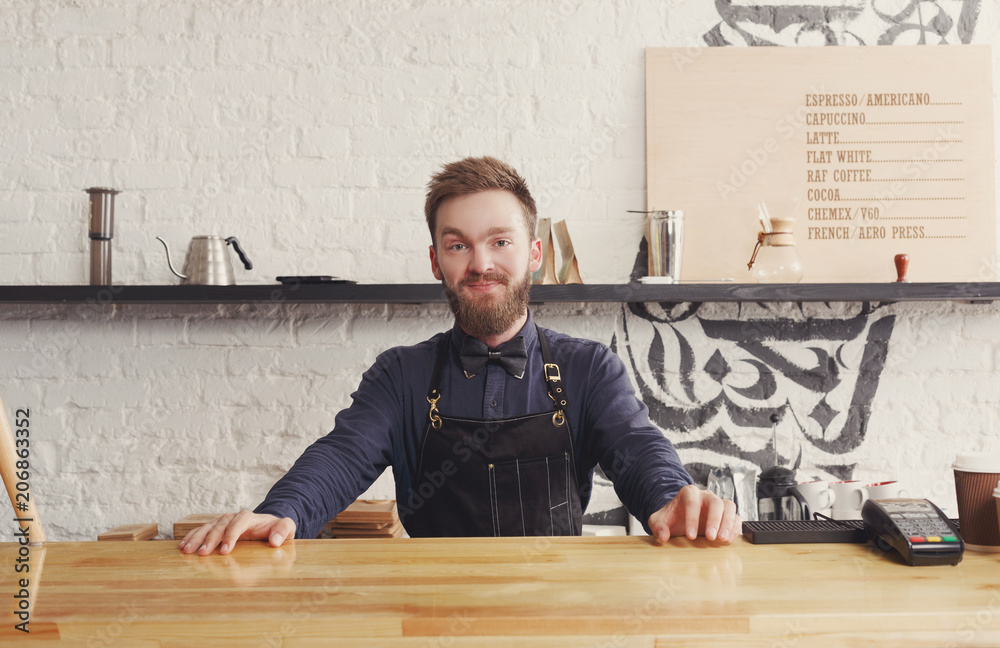 Portrait of young barman at coffee shop counter