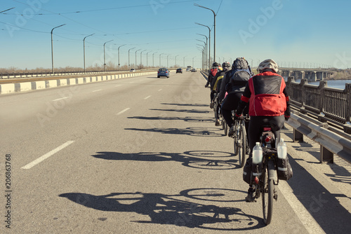 Group of active tourists riding bikes on asphalt road