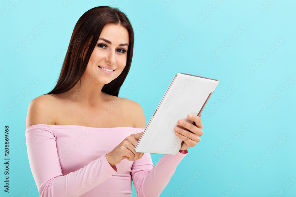 Woman using tablet against blue wall background Woman using tablet against blue wall background
