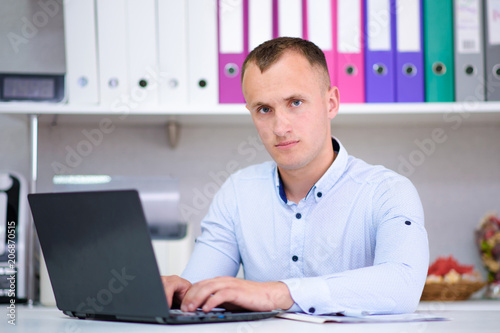 Portrait of a young male manager at the office with a laptop