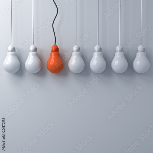 Billede på lærred Think different concept , One hanging orange light bulb standing out from the unlit white lightbulbs on white wall background , leadership and individuality creative idea concepts