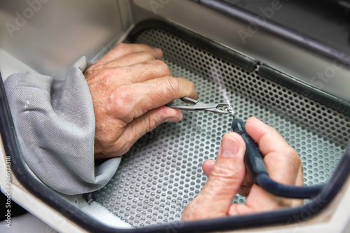 Old men hands working with with tooth prosthesis in  a dental sandblaster