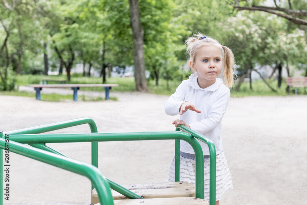 Little girl spins the carousel to ride at the playground Little girl spins the carousel to ride at the playground