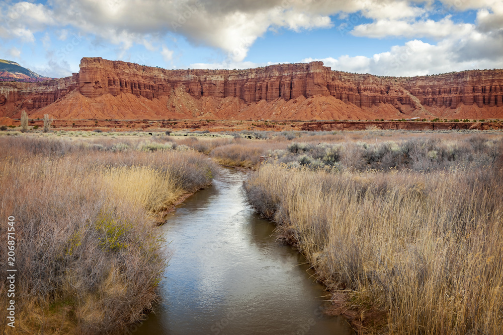 Fremont River Flowing Under Red Sandstone Cliff.  Fly Fishing Utah’s Fremont River is the crown jewel of less traveled trophy waters which meander through red bluffs near the Capitol Reef Park.