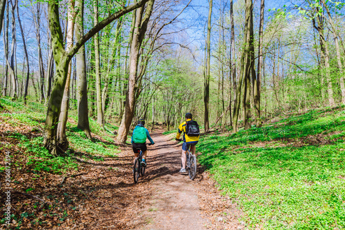 couple riding bicycle in forest in warm day