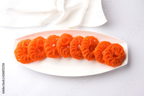 Indian sweet Imarti or Jalebi served in white ceramic plate over white background photo