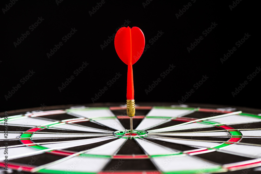 Fototapeta premium Close up shot red darts arrows in the target center on black background. Business target or goal success and winner concept.