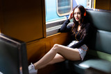 Charming beautiful woman is traveling on retro train and listening nice music during gorgeous woman is going back home. She puts her legs on chair and feels comfortable and relaxed. train background