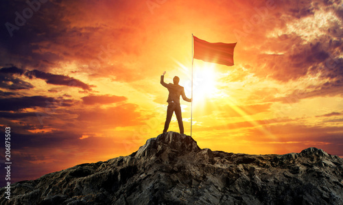 Businessman with flag on mountain top. Concept for success.